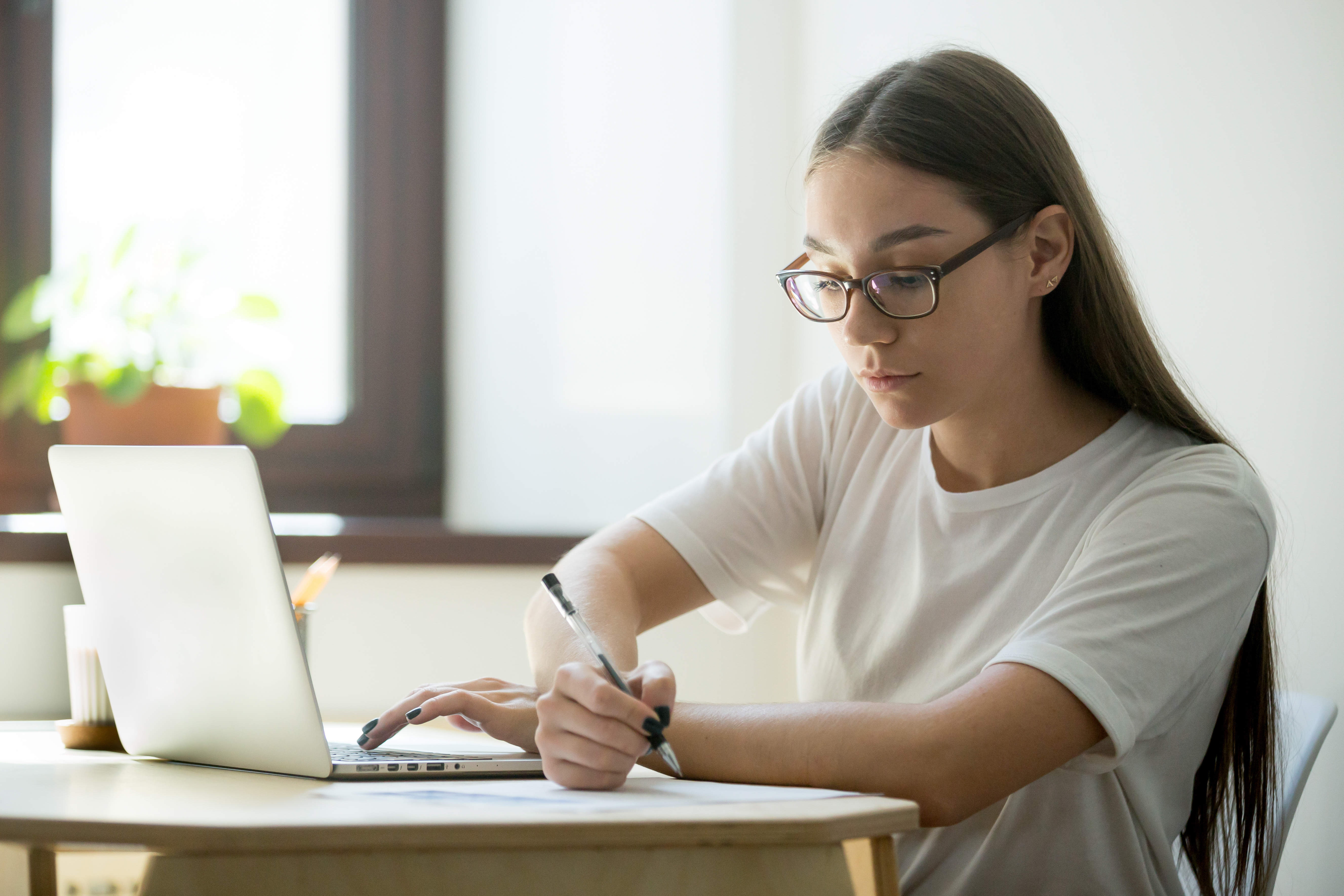 Joven toma apuntes mientras recibe clases virtualmente